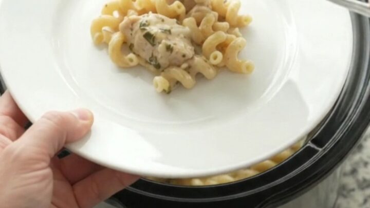 Creamy Crockpot chicken cavatappi with melted cheese and herbs in a black slow cooker