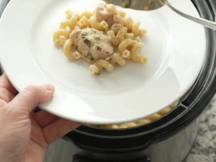 Creamy Crockpot chicken cavatappi with melted cheese and herbs in a black slow cooker