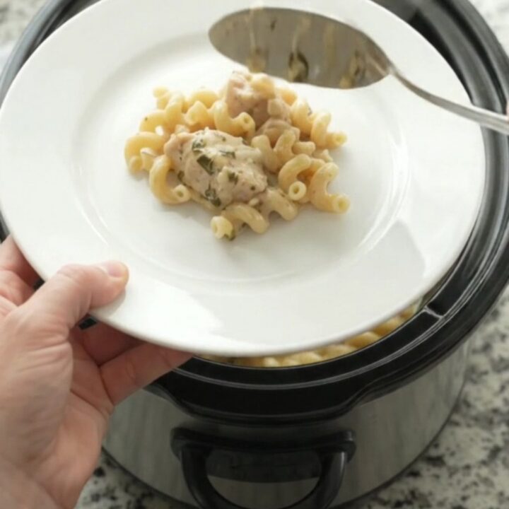 Creamy Crockpot chicken cavatappi with melted cheese and herbs in a black slow cooker
