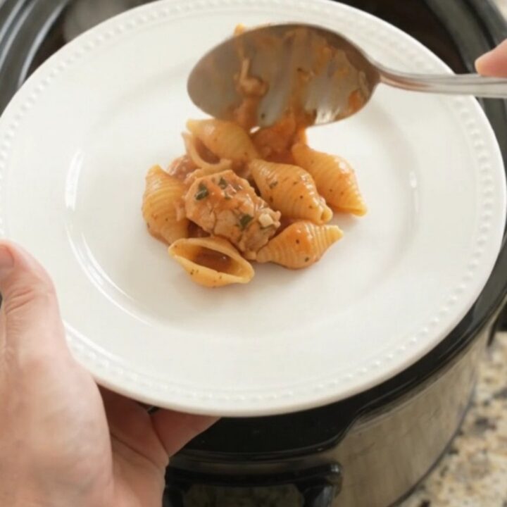 Slow cooker chicken and pasta shells in creamy red pepper sauce topped with melted provolone