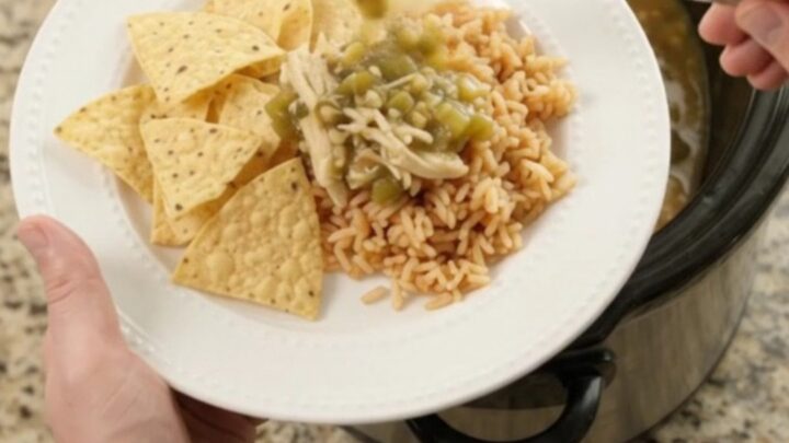 Pepper Jack Salsa Verde Fiesta Chicken bubbling in a slow cooker, with creamy green sauce and shredded chicken
