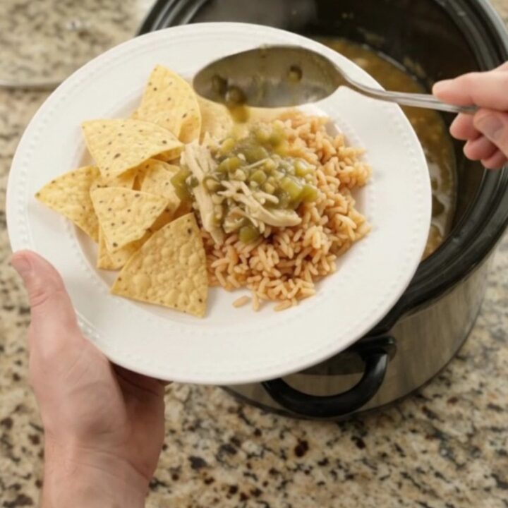 Pepper Jack Salsa Verde Fiesta Chicken bubbling in a slow cooker, with creamy green sauce and shredded chicken