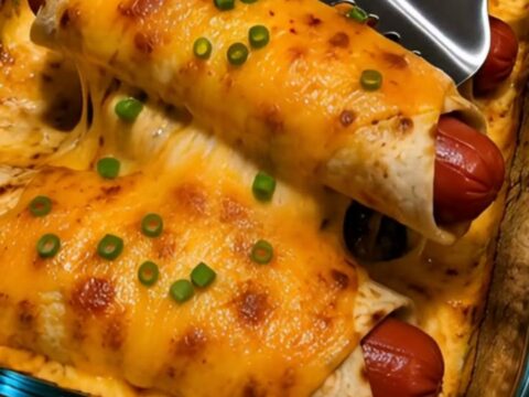 A close-up of a cheesy hot dog tortilla melt showing a dramatic cheese pull with bubbly cheddar and green onions.