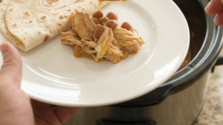 Creamy slow cooker chicken enchilada with melted cheese and beans in a crockpot