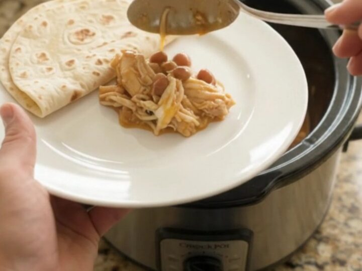 Creamy slow cooker chicken enchilada with melted cheese and beans in a crockpot