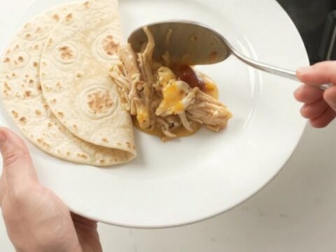 Slow cooker with creamy chipotle pineapple chicken, topped with melted cheese and steam rising