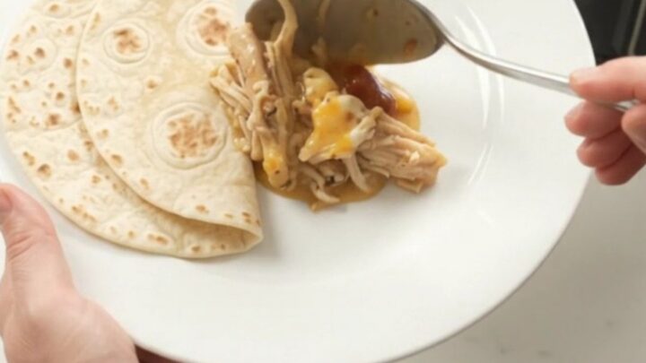 Slow cooker with creamy chipotle pineapple chicken, topped with melted cheese and steam rising