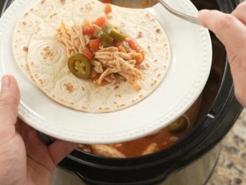 Creamy slow cooker fiesta chicken with melted Monterey Jack and jalapeños in a black Crockpot