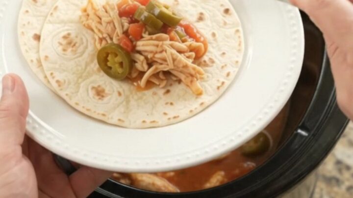 Creamy slow cooker fiesta chicken with melted Monterey Jack and jalapeños in a black Crockpot