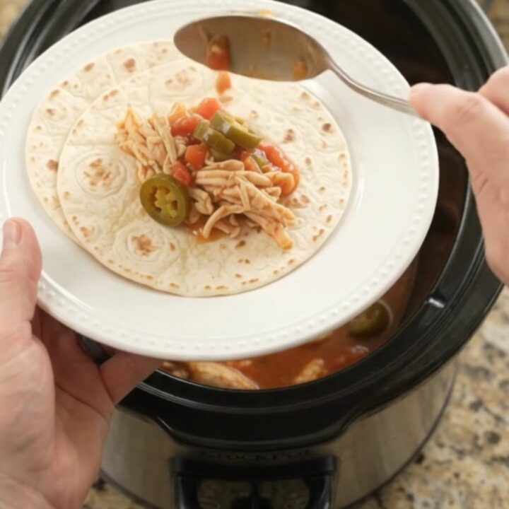 Creamy slow cooker fiesta chicken with melted Monterey Jack and jalapeños in a black Crockpot