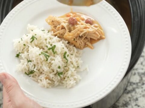 Crockpot fiesta chicken with creamy cheese sauce, shredded chicken, and pinto beans in a slow cooker.