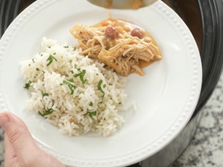 Crockpot fiesta chicken with creamy cheese sauce, shredded chicken, and pinto beans in a slow cooker.
