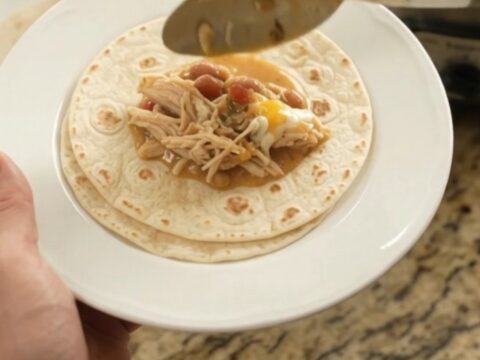 Creamy Crockpot taco fiesta chicken with pinto beans and melted cheese in a slow cooker