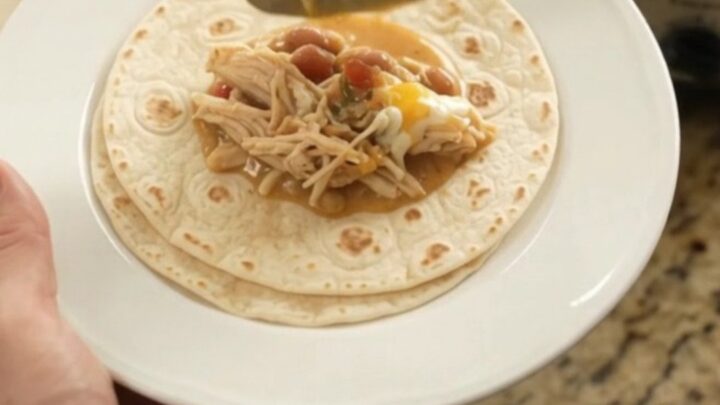 Creamy Crockpot taco fiesta chicken with pinto beans and melted cheese in a slow cooker