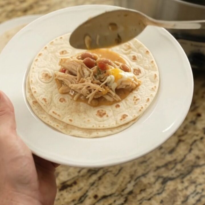 Creamy Crockpot taco fiesta chicken with pinto beans and melted cheese in a slow cooker