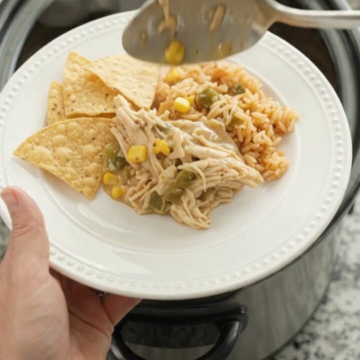 Slow cooker fiesta chicken with creamy queso sauce, green chiles, and corn in a black crockpot
