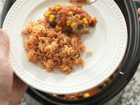 Slow cooker filled with salsa-braised chicken thighs, black beans, corn, and a melted Oaxaca cheese blanket