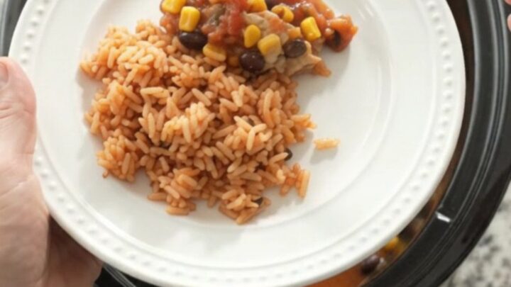 Slow cooker filled with salsa-braised chicken thighs, black beans, corn, and a melted Oaxaca cheese blanket