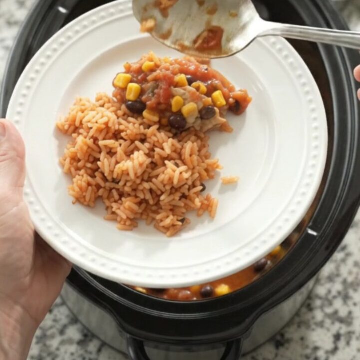 Slow cooker filled with salsa-braised chicken thighs, black beans, corn, and a melted Oaxaca cheese blanket