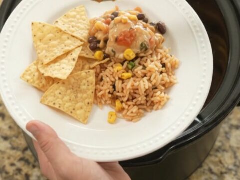Slow cooker full of tender chicken thighs in creamy pepper jack queso sauce with black beans and corn