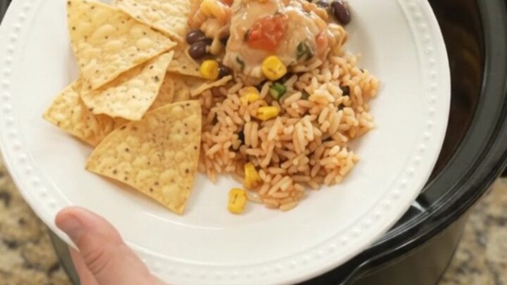 Slow cooker full of tender chicken thighs in creamy pepper jack queso sauce with black beans and corn
