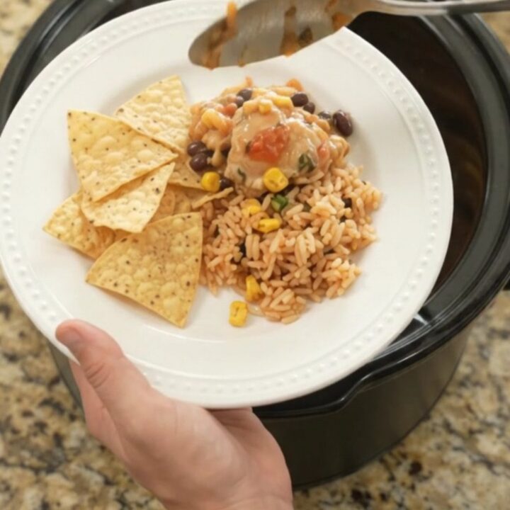 Slow cooker full of tender chicken thighs in creamy pepper jack queso sauce with black beans and corn