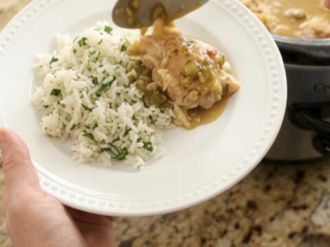 Creamy cheddar salsa verde chicken thighs in a slow cooker with melted cheese and green sauce.