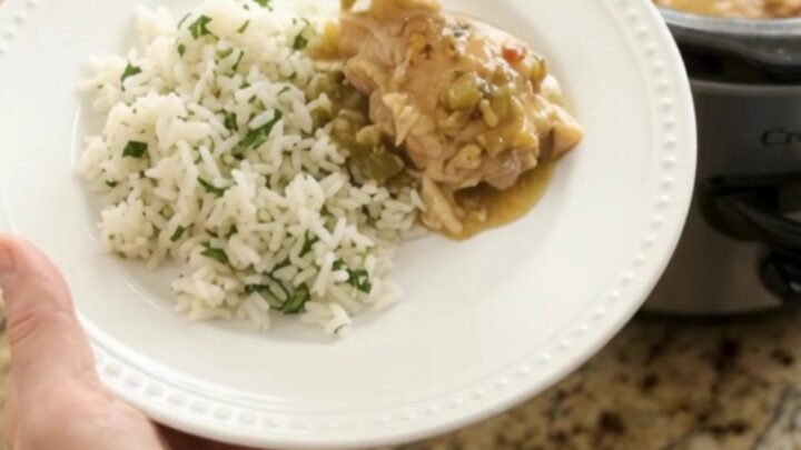 Creamy cheddar salsa verde chicken thighs in a slow cooker with melted cheese and green sauce.