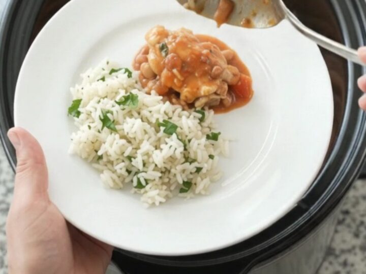 Slow cooker filled with creamy red enchilada chicken and pinto beans, topped with melted cheddar