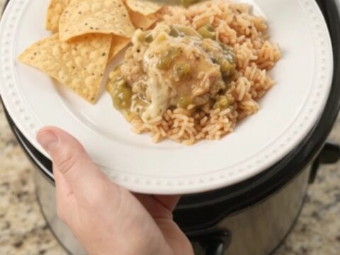 Slow cooker filled with shredded chicken in creamy salsa verde and melted cheese, topped with cilantro.