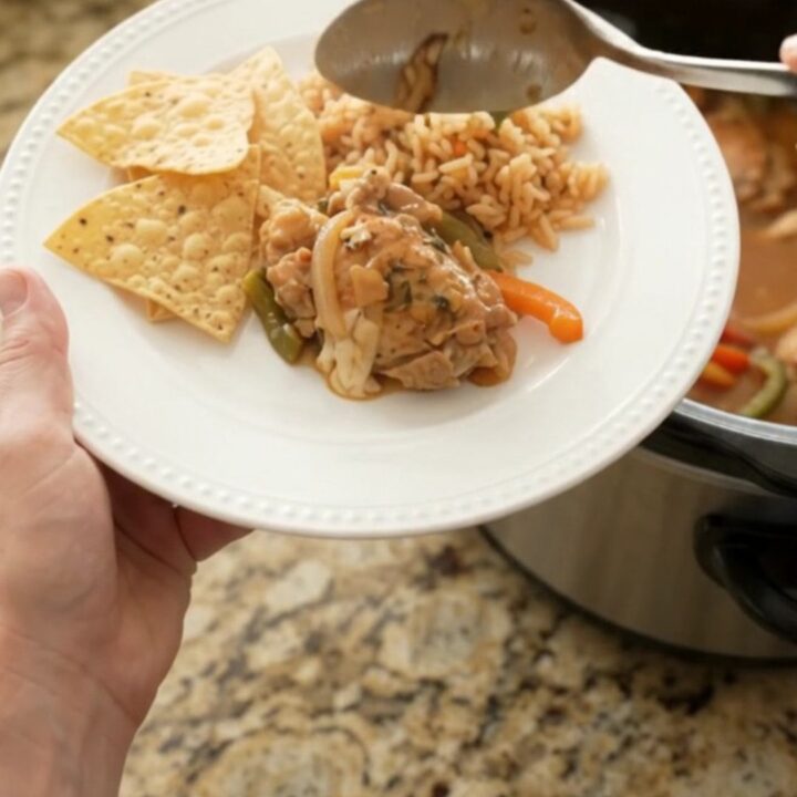 Slow cooker chicken thighs in creamy pepper jack queso sauce with bell peppers and onions