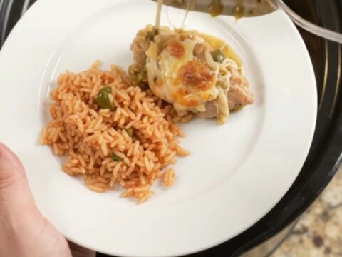 Slow cooker full of salsa verde chicken thighs topped with melted Oaxaca cheese and bubbling green sauce.