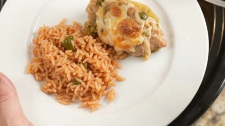 Slow cooker full of salsa verde chicken thighs topped with melted Oaxaca cheese and bubbling green sauce.