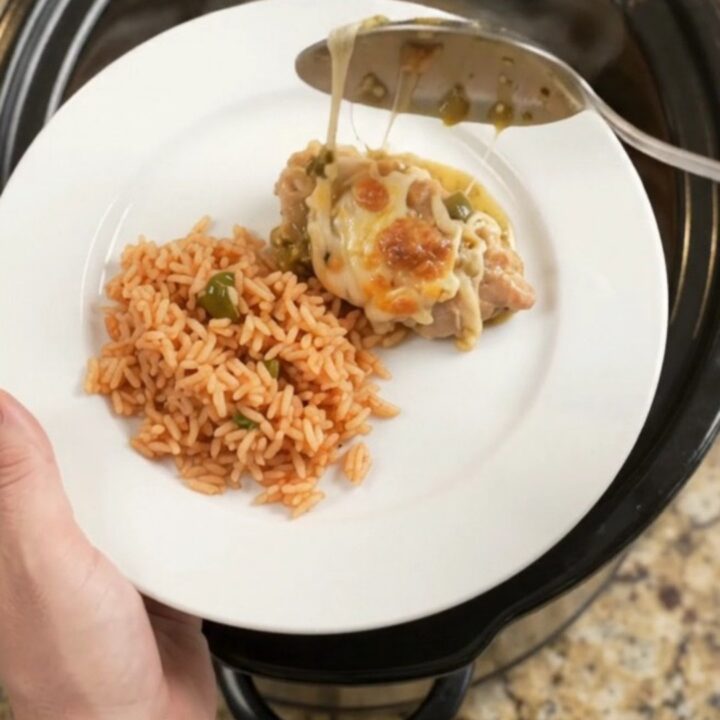 Slow cooker full of salsa verde chicken thighs topped with melted Oaxaca cheese and bubbling green sauce.