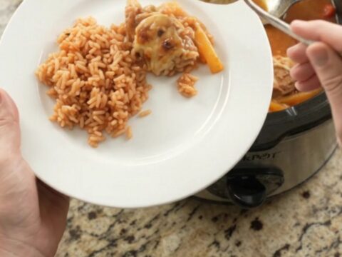 Slow cooker filled with cheesy salsa chicken and peppers, with melted Oaxaca cheese on top