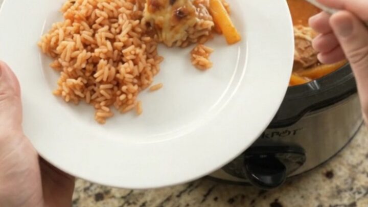 Slow cooker filled with cheesy salsa chicken and peppers, with melted Oaxaca cheese on top