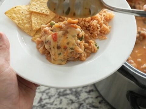 Slow cooker filled with bubbling chipotle pineapple chicken thighs in creamy pepper jack queso sauce
