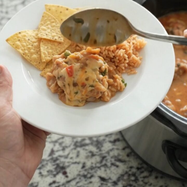 Slow cooker filled with bubbling chipotle pineapple chicken thighs in creamy pepper jack queso sauce