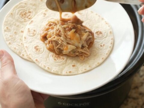 Creamy chipotle pineapple chicken thighs in a slow cooker, topped with melted Monterey Jack and steam rising.