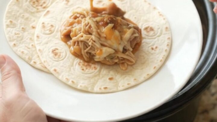 Creamy chipotle pineapple chicken thighs in a slow cooker, topped with melted Monterey Jack and steam rising.