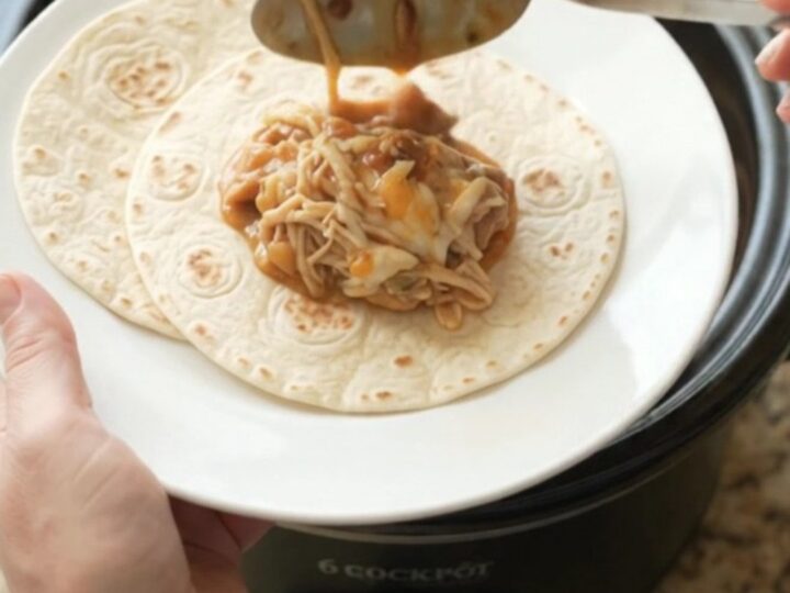Creamy chipotle pineapple chicken thighs in a slow cooker, topped with melted Monterey Jack and steam rising.