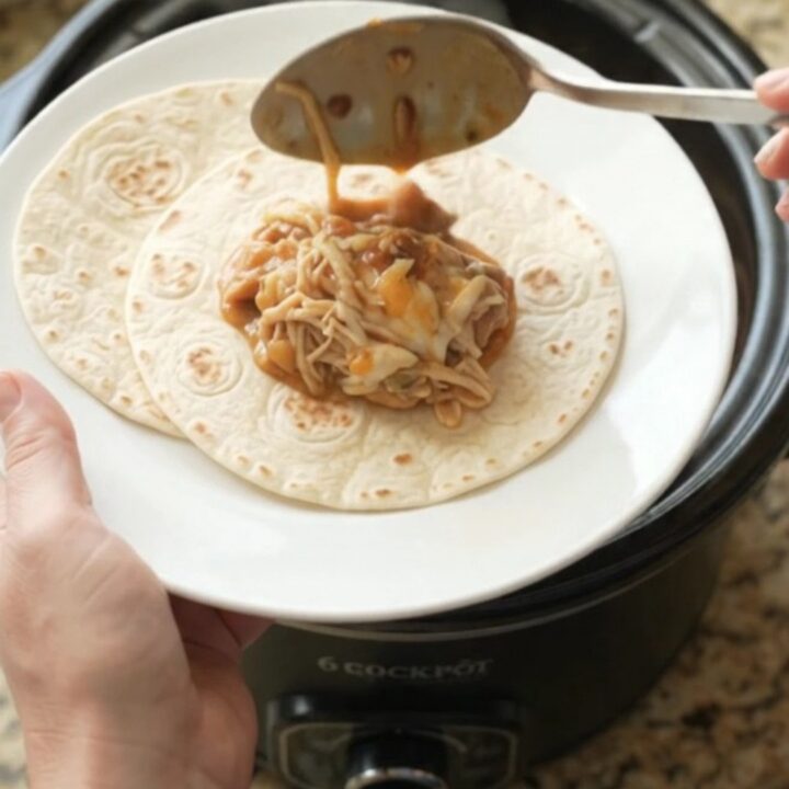 Creamy chipotle pineapple chicken thighs in a slow cooker, topped with melted Monterey Jack and steam rising.
