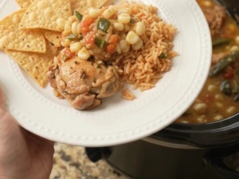 Bubbling slow cooker filled with chicken thighs, hominy, and melted pepper jack queso sauce.