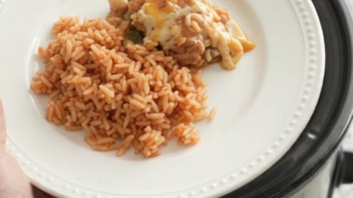 Slow cooker filled with cheesy chicken and hominy stew, bubbling with melted Oaxaca cheese