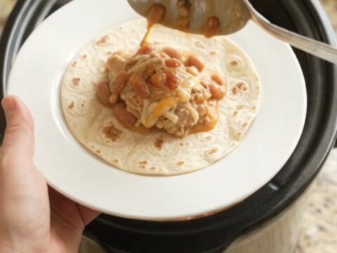Slow cooker chicken thighs with pinto beans and melted Monterey Jack cheese, served with warm tortillas