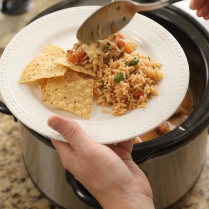 Slow cooker filled with creamy pepper jack mango habanero chicken, topped with melted cheese and cilantro