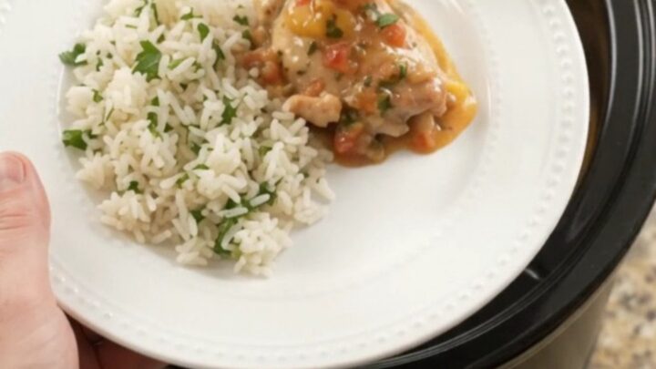 Creamy cheddar mango habanero chicken thighs in a slow cooker with melted cheese and mango pieces.