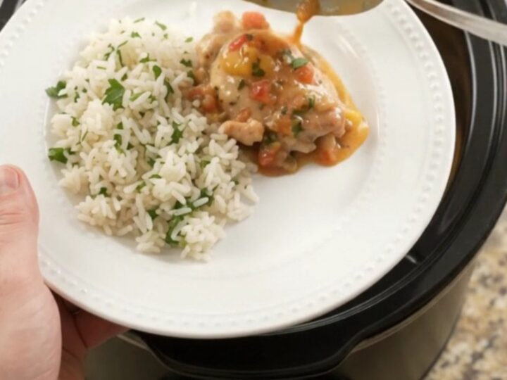 Creamy cheddar mango habanero chicken thighs in a slow cooker with melted cheese and mango pieces.
