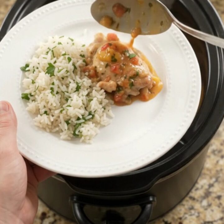 Creamy cheddar mango habanero chicken thighs in a slow cooker with melted cheese and mango pieces.
