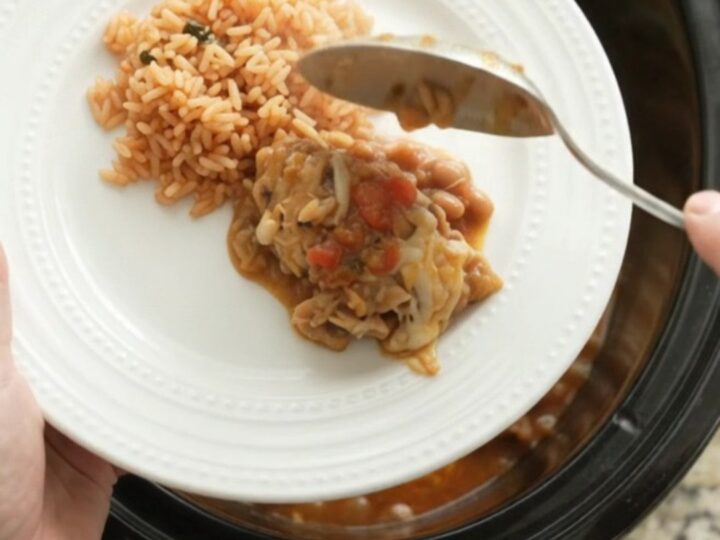 Slow cooker filled with shredded chicken, beans, and melted Oaxaca cheese, topped with blistered cheese.
